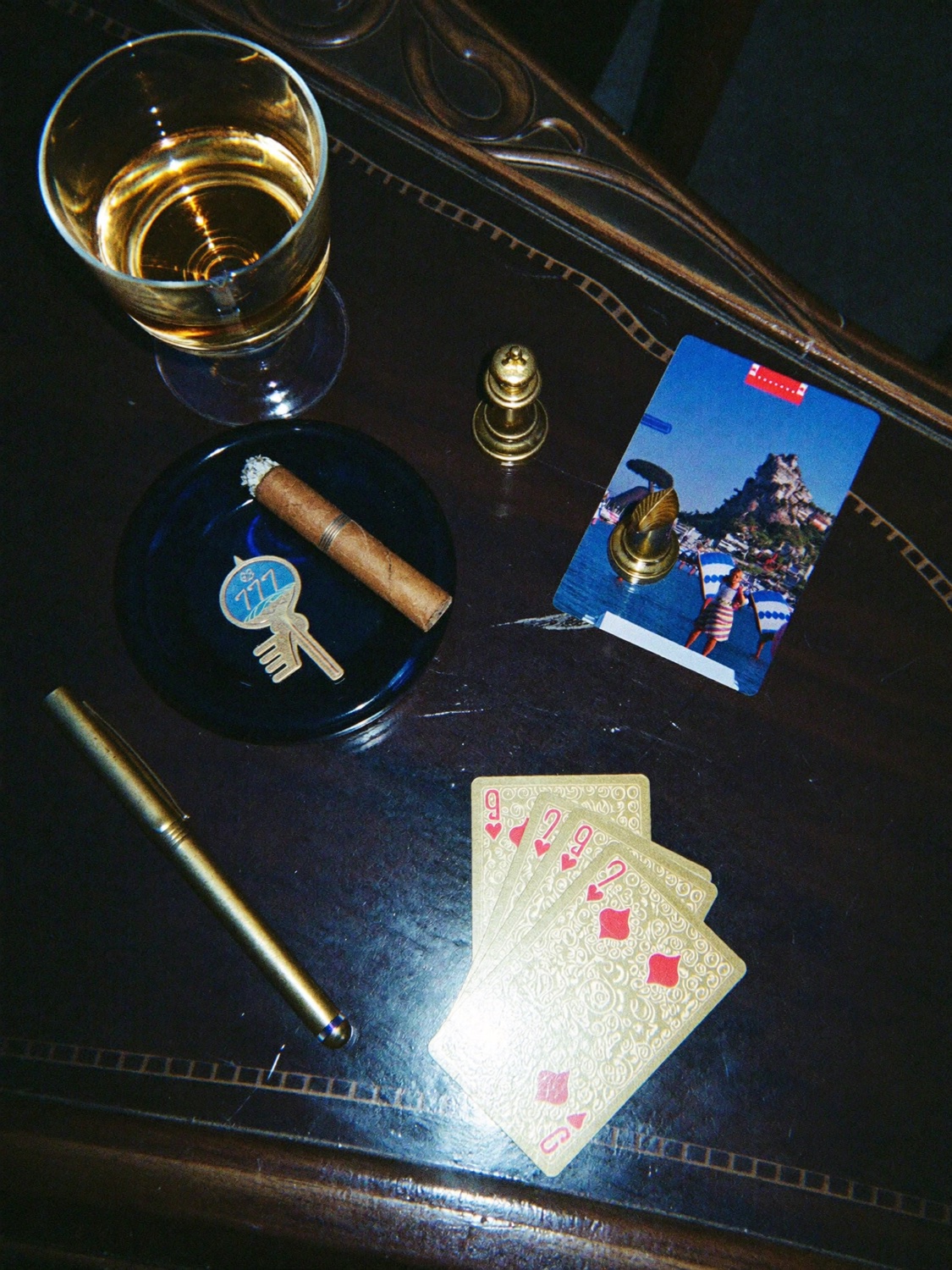 Nature morte sur acajou : whisky, cigare, cartes à jouer dorées et stylo or